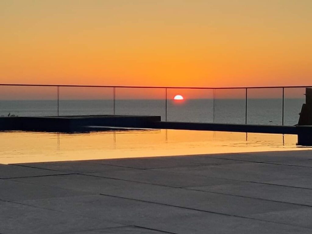 Serene sunset over ocean with pool reflection.