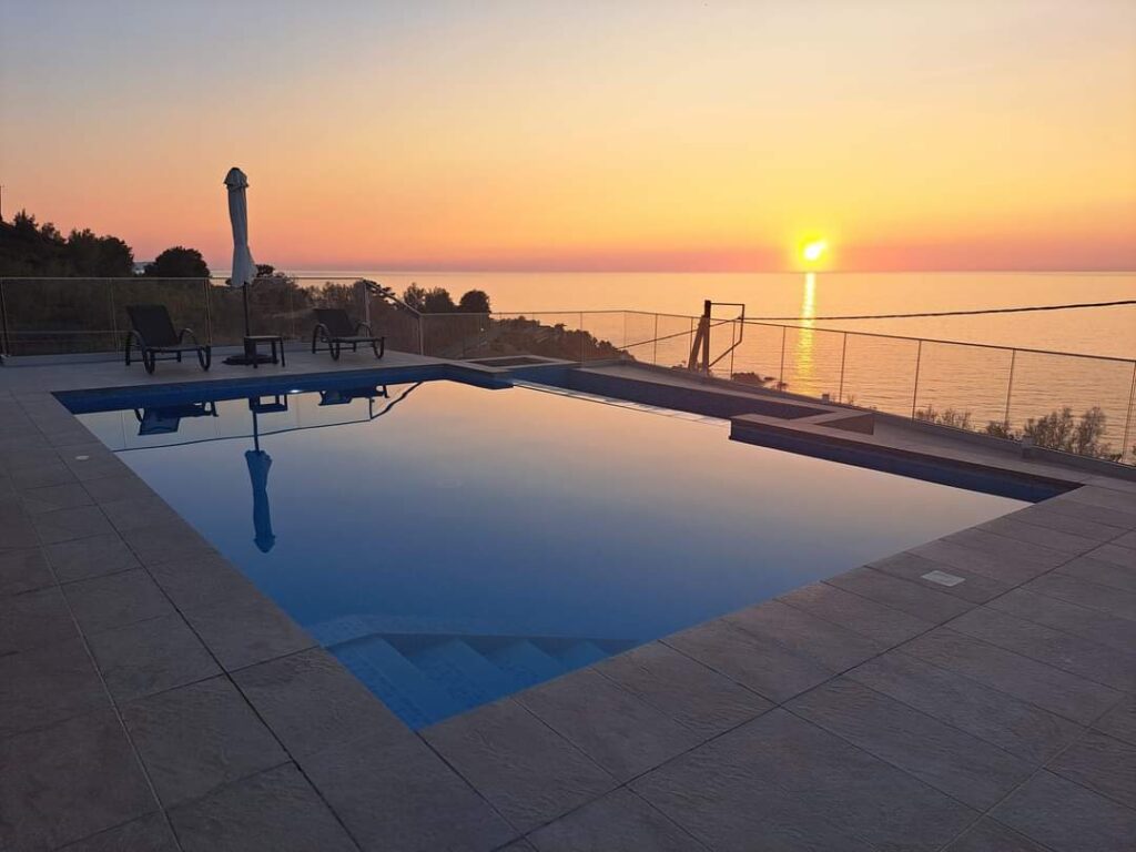 Sunset reflecting in swimming pool overlooking ocean view.